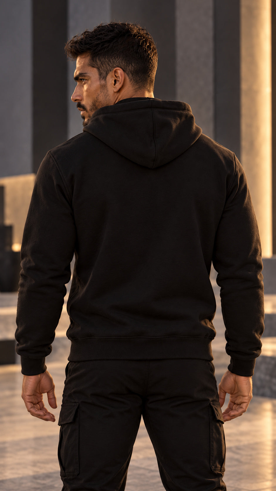 Back view of the black AET Core Hoodie worn by Rael Noir