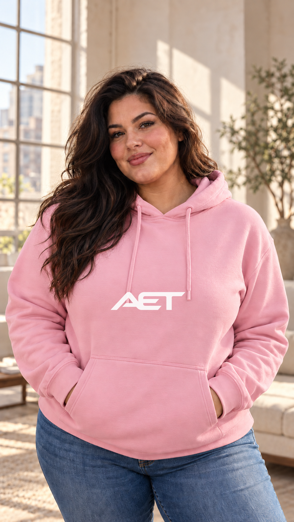 Valentina wearing the AET Core Hoodie in Light Pink, featuring the connected AET wordmark.
